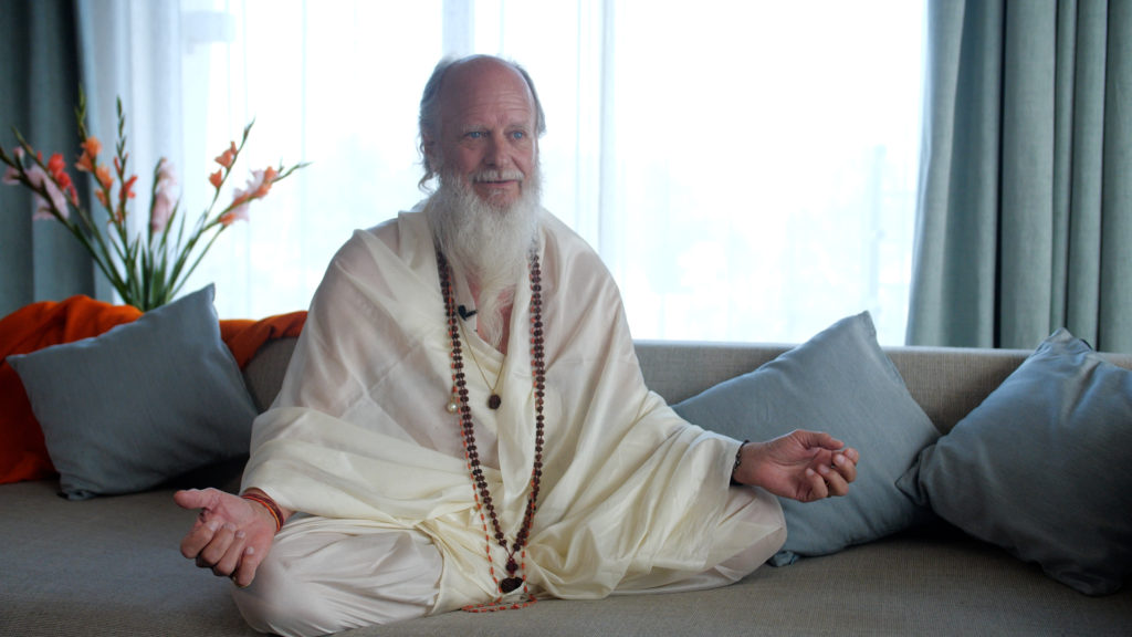 Thom Knoles, master of Vedic Meditation, sitting cross-legged with arms open