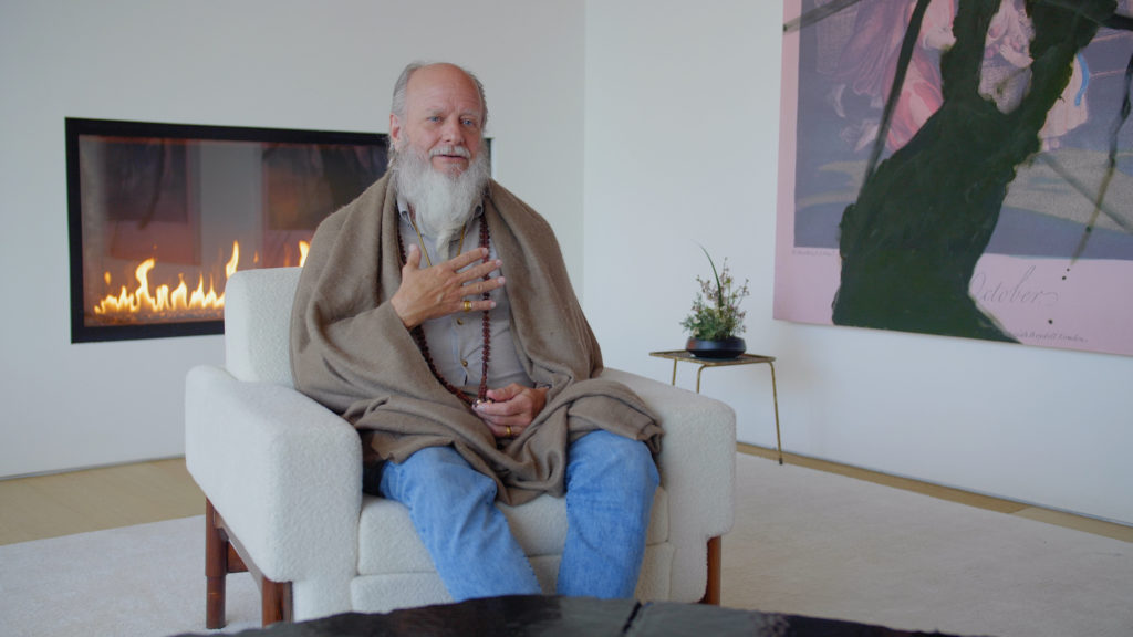 Thom Knoles, Vedic Meditation master sitting by a fireplace