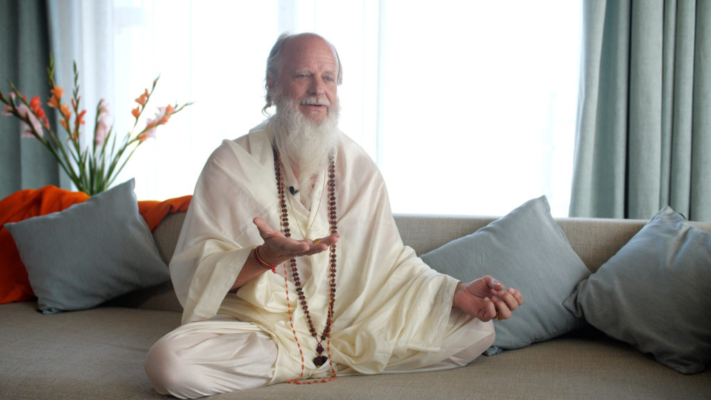 Thom Knoles, master of Vedic Meditation, sitting cross-legged with arms open