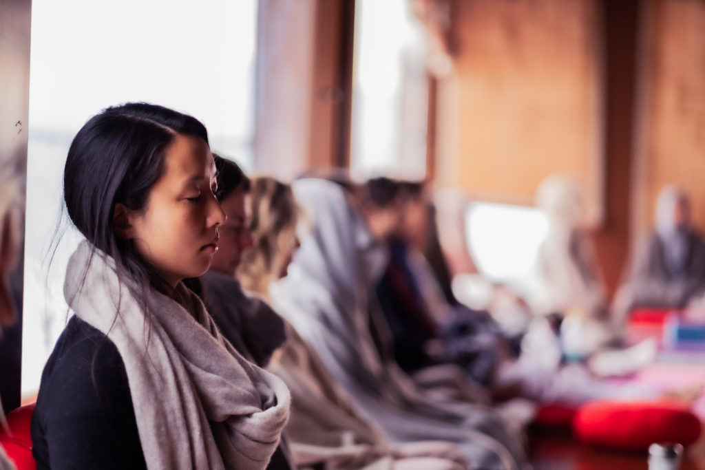 A line of people meditating at a Vedic Meditation Retreat
