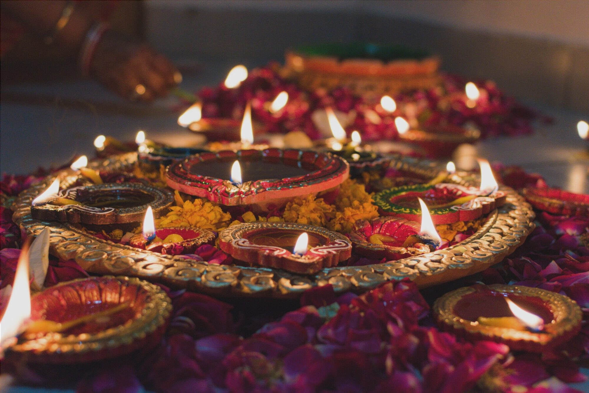 dish of many lit candles and flower petals
